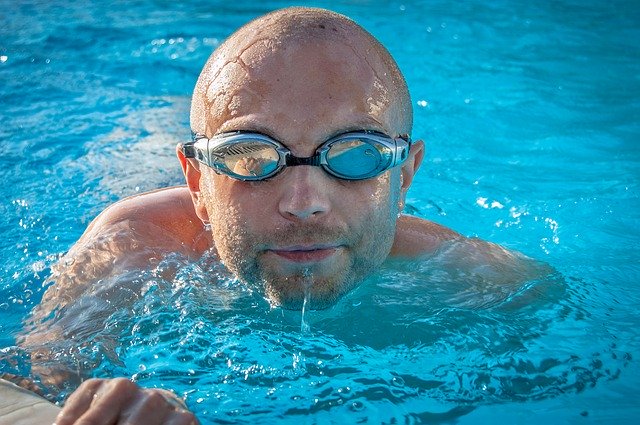 holohlavý muž v bazéně s brýlemi